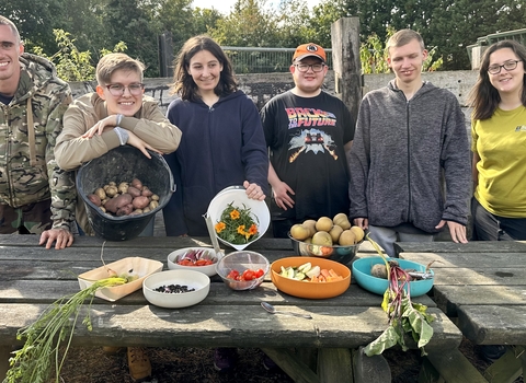 Six young people in a row with their produce on a table